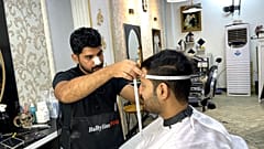 الحلاق العراقي مصطفى الشيرازي يقوم بأخذ قياسات رأس أحد الزبائن