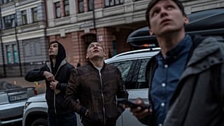 Pedestrians observe Kyiv's air defense systems trying to down a drone in Kyiv, Thursday, May 4, 2023.