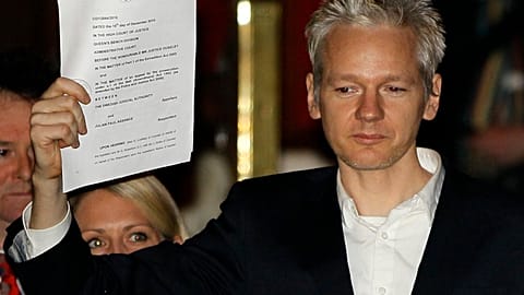 FILE - In this Thursday, Dec. 16, 2010 file photo, WikiLeaks founder Julian Assange holds up a court document for the media after he was released on bail,