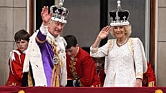 Карл III в Короне Британской Империи и королева Камилла в Короне Марии Текской приветствуют подданных с балкона Букингемского дворца.