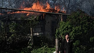 Idős asszony egy égő ház előtt a donyecki bombázások után május 7-én
