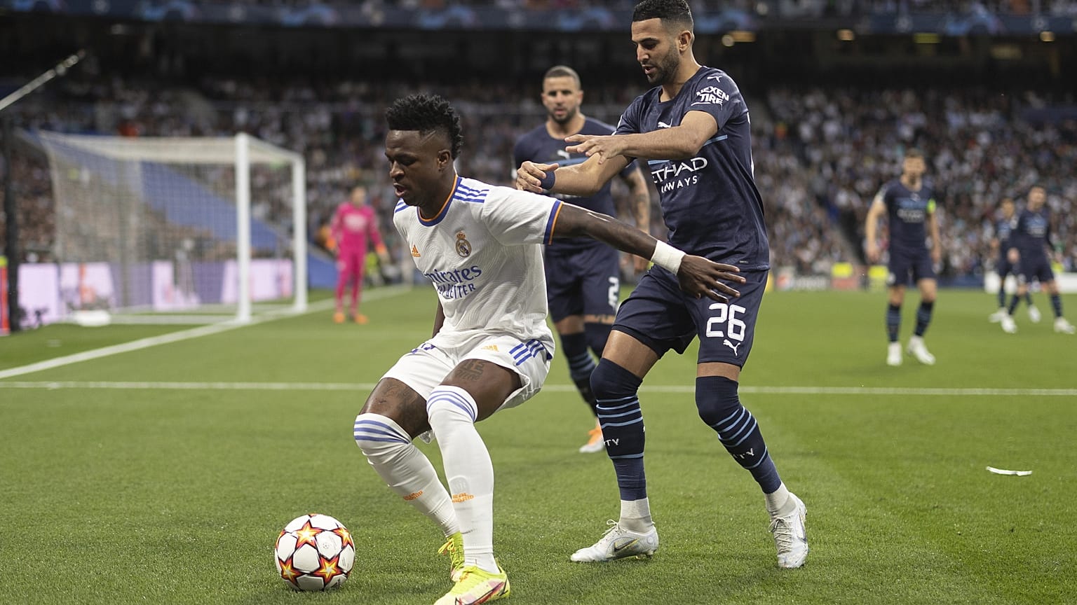 Vinicius Junior (fehérben), a Real Madrid és Riyad Mahrez, a Manchester City játékosa küzd a labdáért a 2022. május 4-i BL-mérkőzésen a madridi Santiago Bernabeu Stadionban.