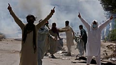Supporters of Pakistan's former Prime Minister Imran Khan gestures as police fire tear gas to disperse them. Peshawar, May 10, 2023