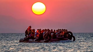 مهاجرون على متن زورق يصلون إلى جزيرة كوس جنوب شرق اليونان بعد عبورهم من تركيا، يوم الخميس 13 أغسطس 2015.