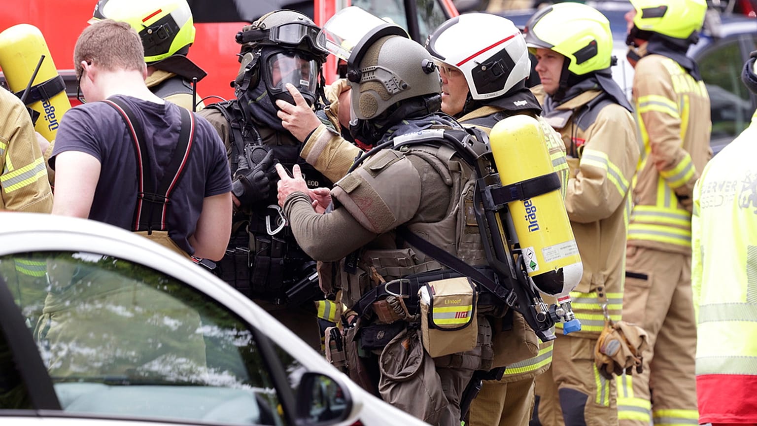 Police officers wearing gas masks and firefighters stand in front of a residential building in Ratingen, Germany, Thursday May 11, 2023. 