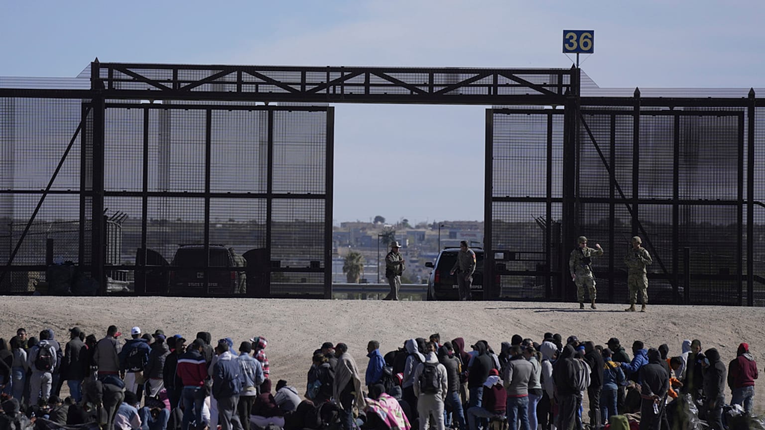 Migrants who crossed the border from Mexico into the U.S. wait next to the U.S. border wall. Seen from Ciudad Juarez, Mexico, March 30, 2023