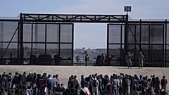 Migrants who crossed the border from Mexico into the U.S. wait next to the U.S. border wall. Seen from Ciudad Juarez, Mexico, March 30, 2023