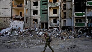 A soldier walks past a building destroyed by attacks in Chernihiv