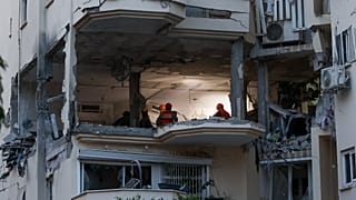 La police et les forces de secours sur les lieux où une roquette tirée de Gaza a touché et endommagé un bâtiment à Rehovot