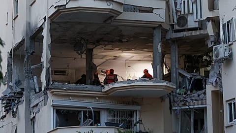 La police et les forces de secours sur les lieux où une roquette tirée de Gaza a touché et endommagé un bâtiment à Rehovot