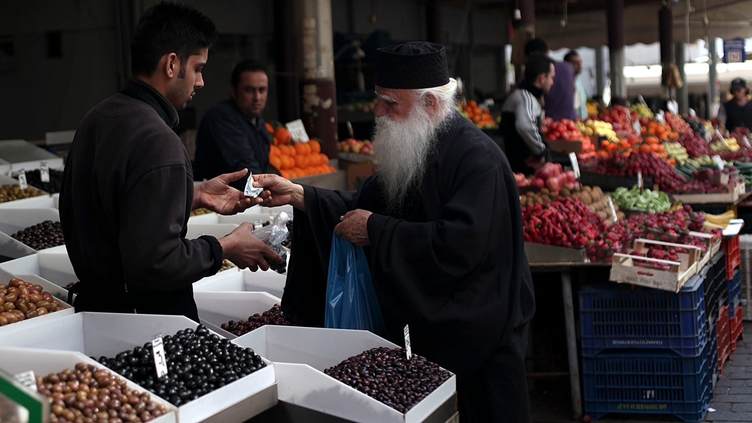 Ein Priester kauft Oliven auf einem Markt in Athen