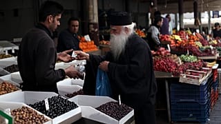 Ein Priester kauft Oliven auf einem Markt in Athen