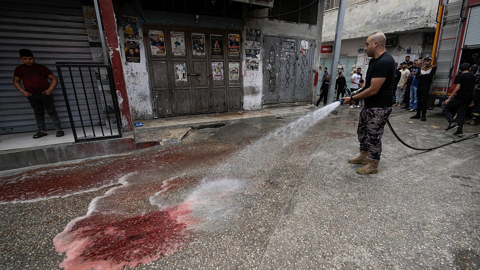 رجل إطفاء فلسطيني يزيل دماء الشابين الفلسطينيين اللذين قتلا برصاص إسرائيلي بمخيم بلاطة