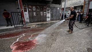 رجل إطفاء فلسطيني يزيل دماء الشابين الفلسطينيين اللذين قتلا برصاص إسرائيلي بمخيم بلاطة