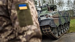 A Ukrainian soldier is standing in front of a Marder infantry fighting vehicle at the German forces Bundeswehr training area in Munster, Germany