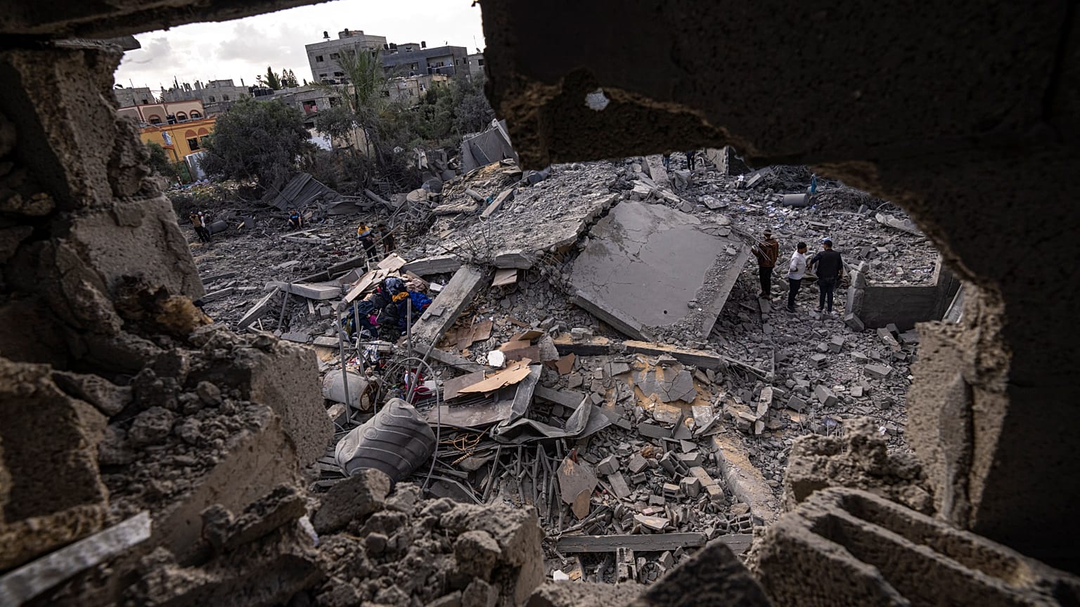 فلسطينيون يتفقدون الأنقاض في موقع غارة جوية قال الجيش الإسرائيلي إنها استهدفت منزل أحد أعضاء الجهاد الإسلامي في دير البلح. 2023/05/13