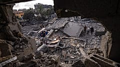 فلسطينيون يتفقدون الأنقاض في موقع غارة جوية قال الجيش الإسرائيلي إنها استهدفت منزل أحد أعضاء الجهاد الإسلامي في دير البلح. 2023/05/13