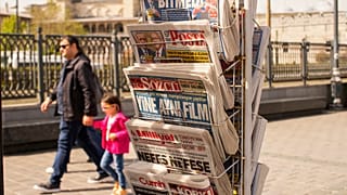 People walk past a rack with Turkish newspapers a day after the presidential election day, in Istanbul, Turkey, Monday, May 15, 2023.