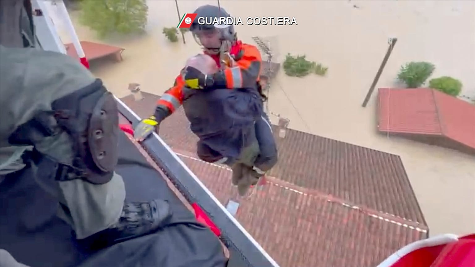 Un guardacostas desciende de un helicóptero para rescatar a un hombre sobre un tejado, en Faenza