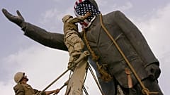 ABD'li asker, 9 Nisan 2003'te Irak'ın başkenti Bağdat'ta Saddam Hüseyin'in heykelini devirmeden önce heykelin yüzünü Amerikan bayrağıyla kapatıyor.