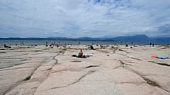 People sunbath on the peninsula of Sirmione, on Garda lake, Italy, Friday, Aug. 12, 2022.
