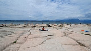 People sunbath on the peninsula of Sirmione, on Garda lake, Italy, Friday, Aug. 12, 2022.