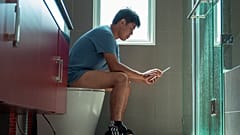 Un homme assis sur les toilettes. 