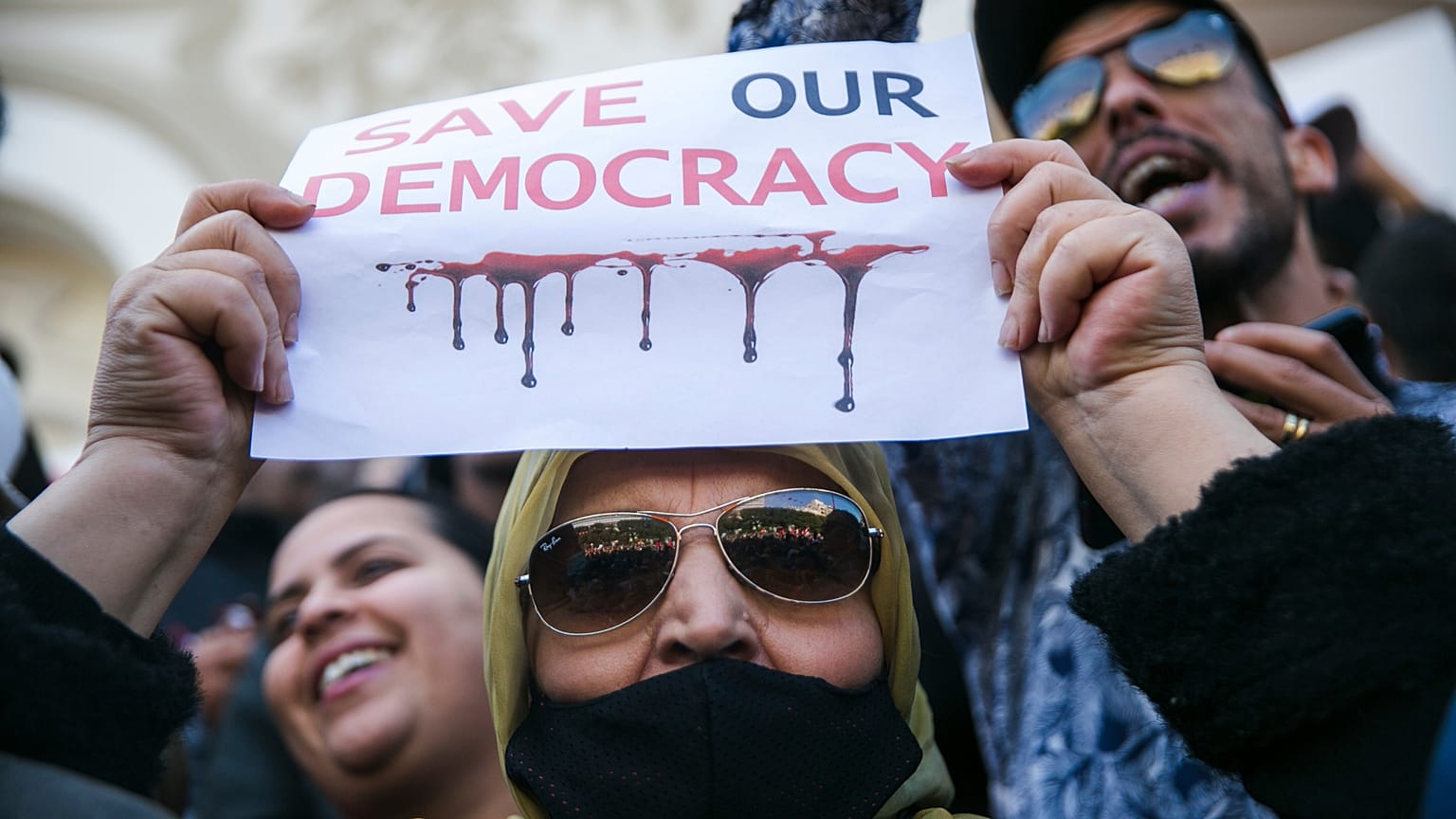 A woman holds up a banner during a protest against Tunisian President Kais Saied, in Tunis, Tunisia, Sunday, April 10, 2022. 