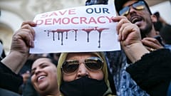 A woman holds up a banner during a protest against Tunisian President Kais Saied, in Tunis, Tunisia, Sunday, April 10, 2022. 