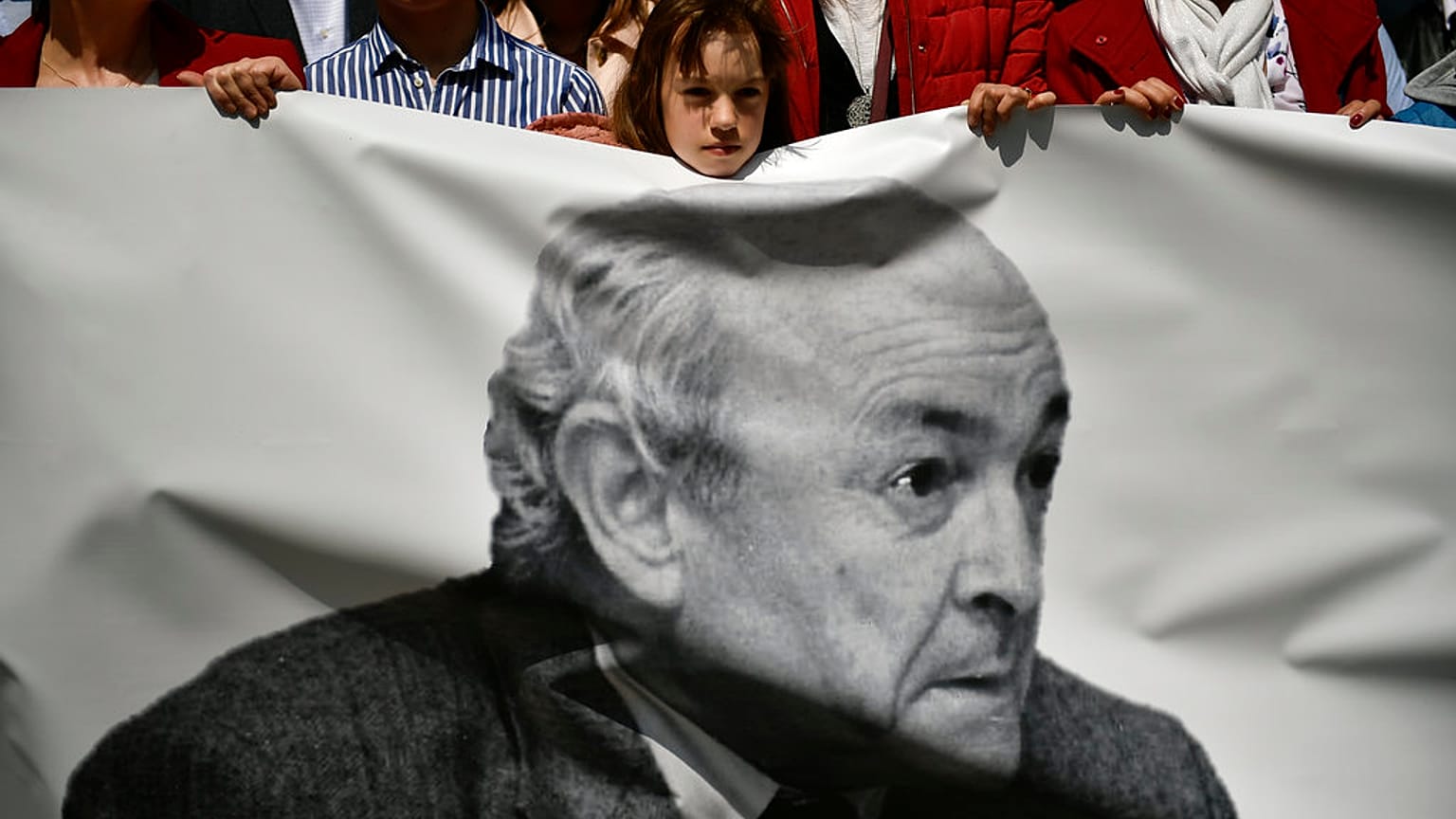 A young girl saves a silence minute in honor of Tomas Caballero, his portrait on the banner, a regional politician of the City Hall killed by ETA.