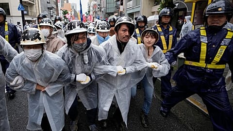 Demonstrierende marschieren durch die Straßen von Hiroshima, umgeben von Polizisten, während eines Protests gegen den G7-Gipfel