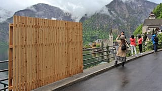 Une clôture provisoire en bois bloquait partiellement la vue magnifique, alors que les visiteurs prennent des selfies avec le paysage du village d'Hallstatt.