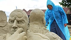 Kirsten Andersen from Denmark braves the rainy weather as she works at her sand sculpture titled "a new perspective on planet earth".