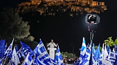 Supporters wave Greek flags as Greece's Prime Minister and New Democracy leader Kyriakos Mitsotakis gestures during his main election campaign rally in Athens.
