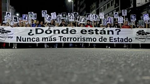 People march in silence carrying photos of the disappeared.