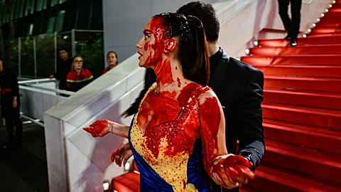 A protester, wearing a dress in the colours of the Ukrainian flag, is detained by security.