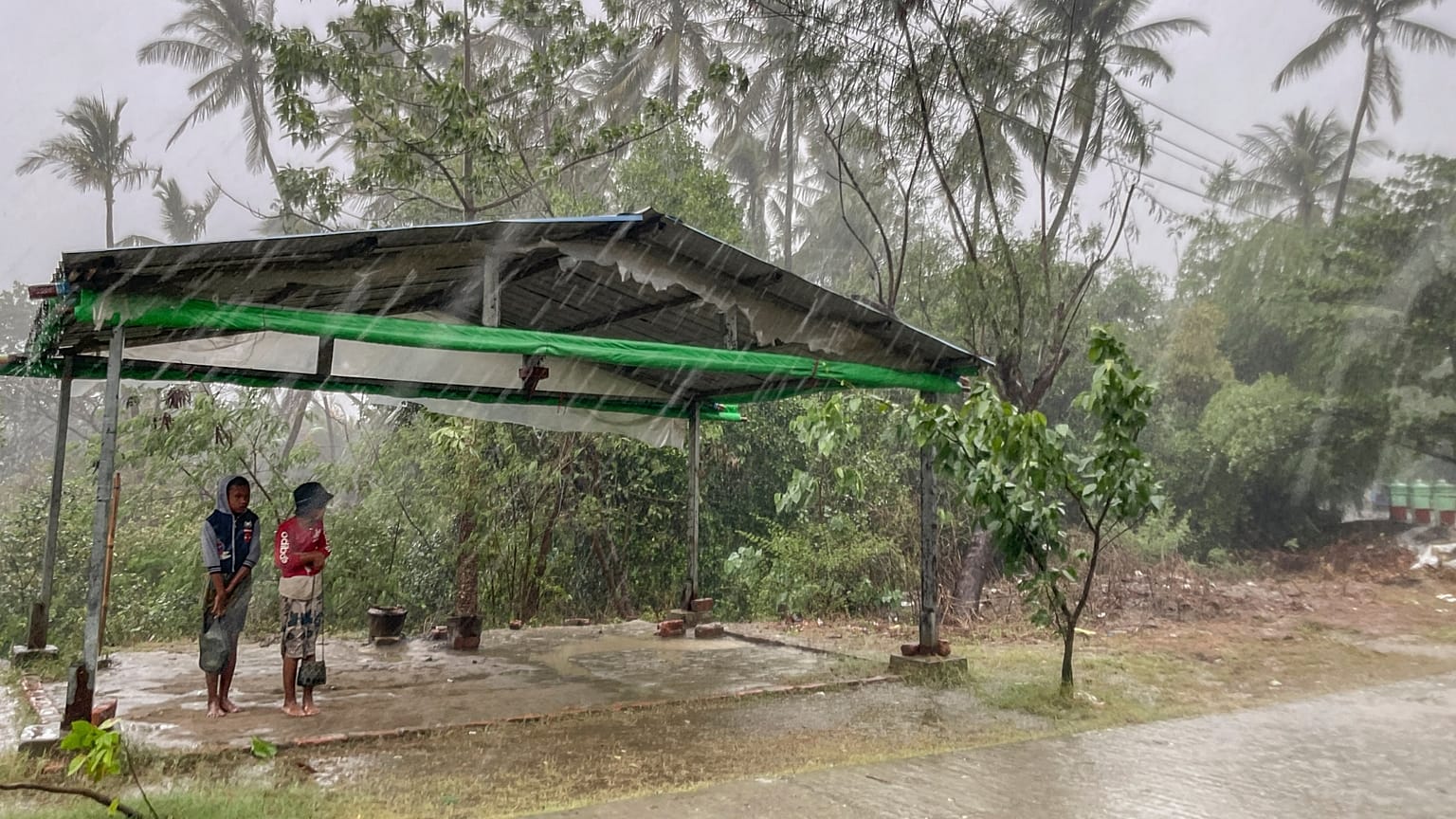 Two children stand under a roadside shelter to protect from rain before Cyclone Mocha hits in Sittwe, Rakhine State.