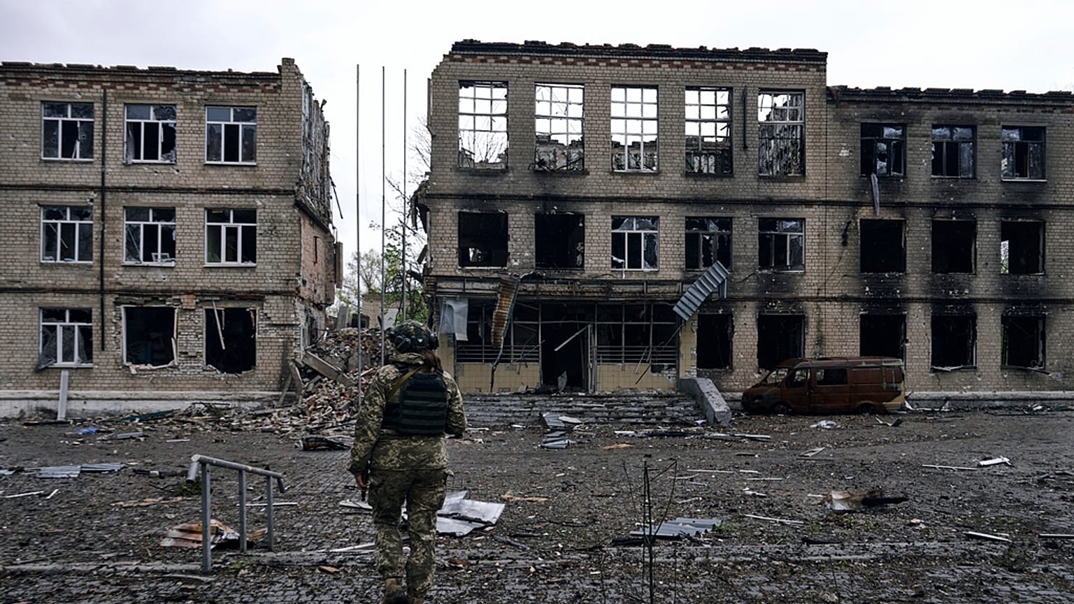 Ukrayna'nın Rus saldırıları altındaki Avdiivka kentinde, yıkık bir binanın önünde yürüyen asker
