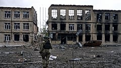 Ukrayna'nın Rus saldırıları altındaki Avdiivka kentinde, yıkık bir binanın önünde yürüyen asker