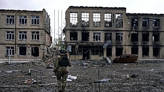 Ukrayna'nın Rus saldırıları altındaki Avdiivka kentinde, yıkık bir binanın önünde yürüyen asker