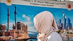 Eine Türkin vor einem Wahllokal, im Hintergrund ein Wahlplakat, das eine türkische Moschee und die Skyline von Frankfurt am Main zeigt. Mittwoch, 24. Mai 2023