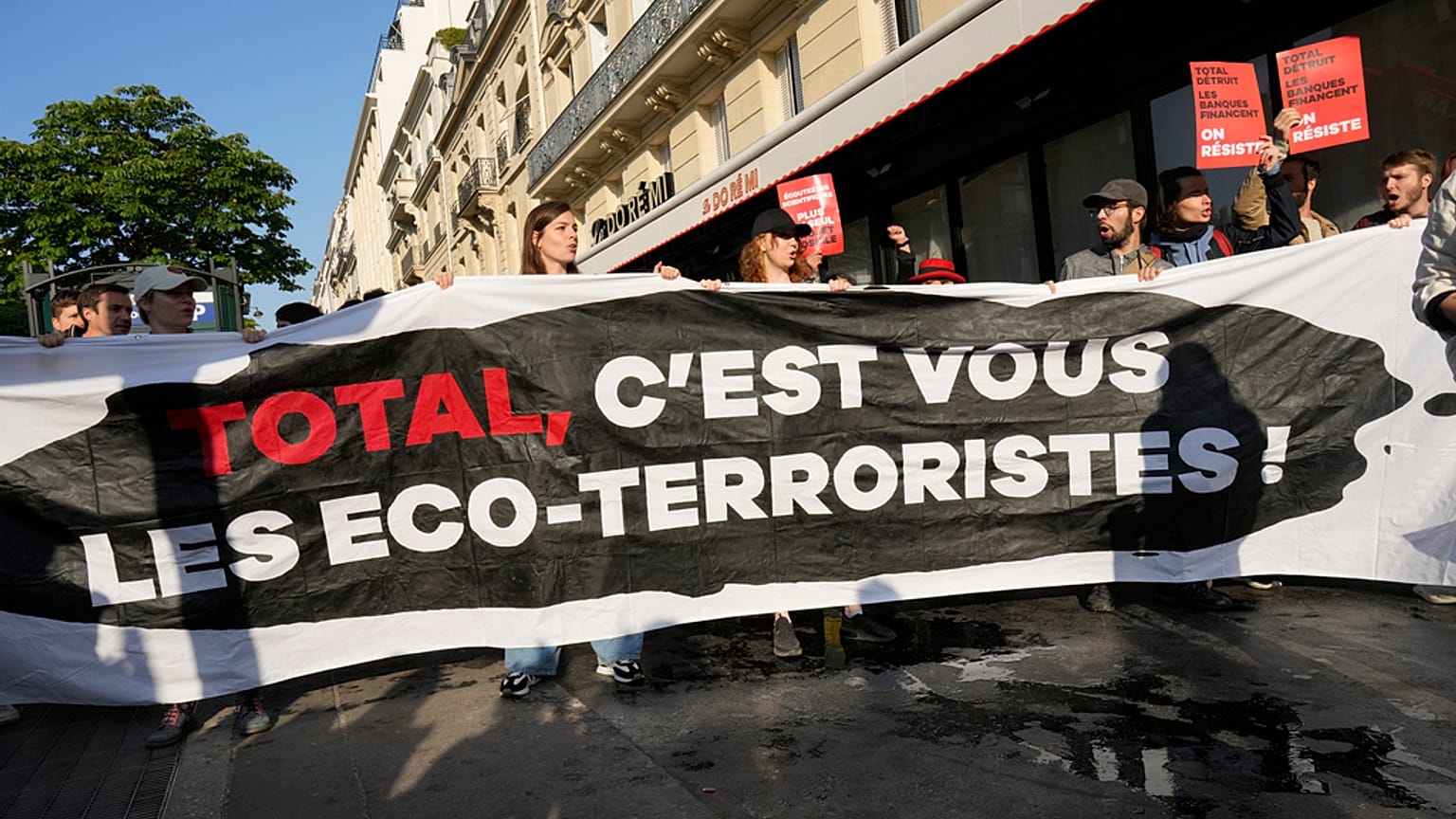 Des manifestants affichent une banderole "Total, vous êtes les éco-terroristes" avant l'AG des actionnaires deTotalEnergies,vendredi 26 mai 2023 à Paris.