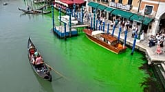 A gondola navigates along Venice's historical Grand Canal as a patch of phosphorescent green liquid spreads in it, Sunday, May 28, 2023