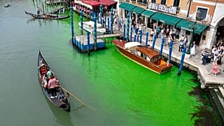 A gondola navigates along Venice's historical Grand Canal as a patch of phosphorescent green liquid spreads in it, Sunday, May 28, 2023