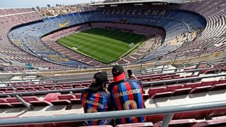 Two Barcelona fans wait for the start of a Spanish La Liga soccer match between Barcelona and Mallorca at the Camp Nou stadium in Barcelona