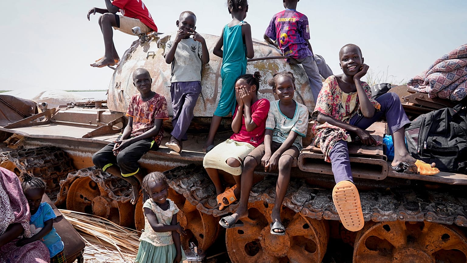 Children sit and play on the remains of a tank, at the river port in Renk, South Sudan Wednesday, May 17, 2023.