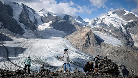 People stand in front of the Pers and Morteratsch glaciers in Pontresina, Switzerland. August 2022. 