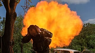 A Ukrainian soldier covers his ears while firing a mortar at Russian positions on the frontline near Bakhmut, Ukraine.