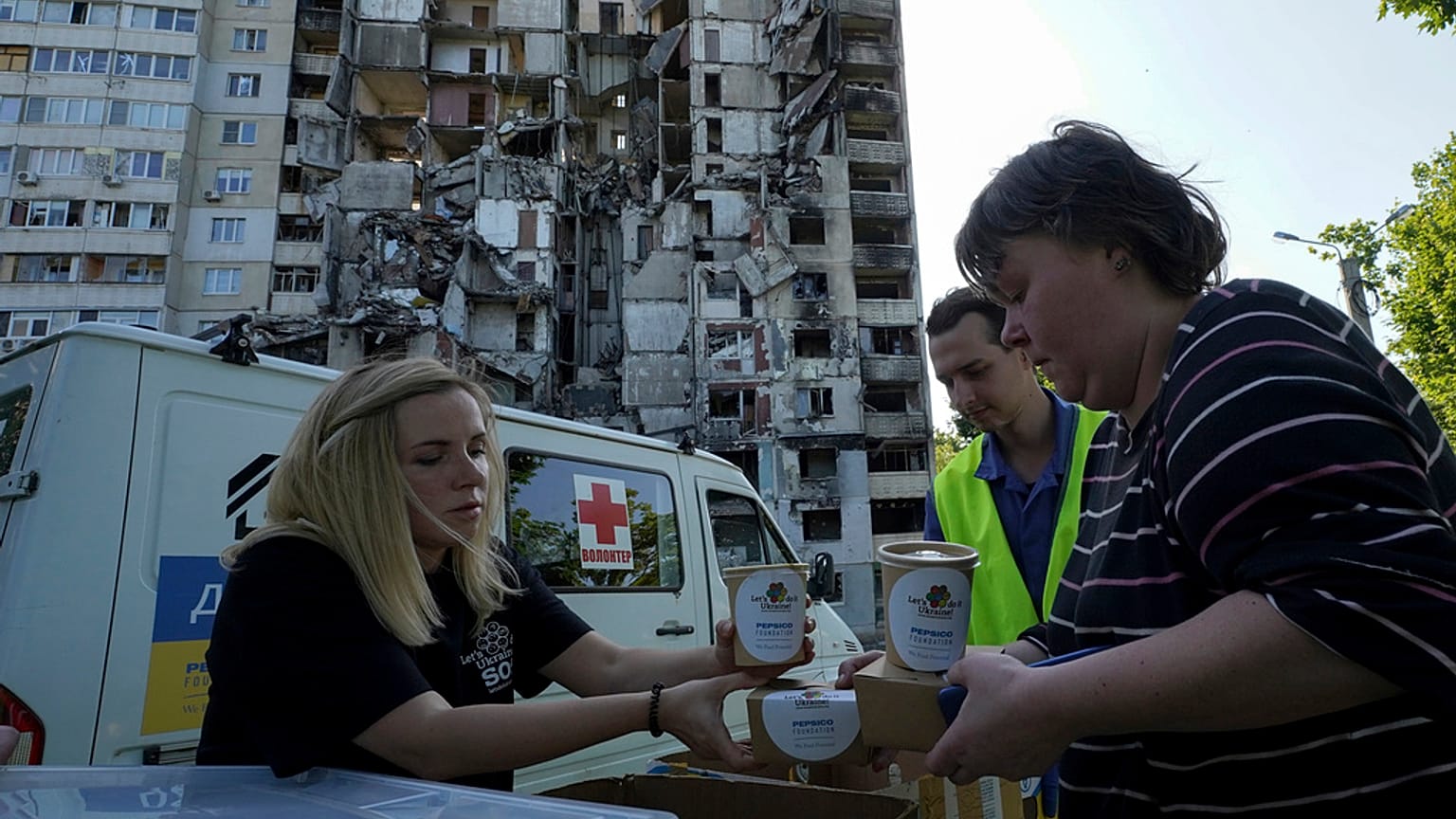 Des habitants reçoivent des repas gratuits sur le fond de leur immeuble endommagé à Kharkiv, en Ukraine, 02/06/2023