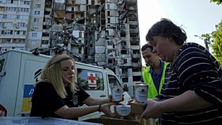 Des habitants reçoivent des repas gratuits sur le fond de leur immeuble endommagé à Kharkiv, en Ukraine, 02/06/2023